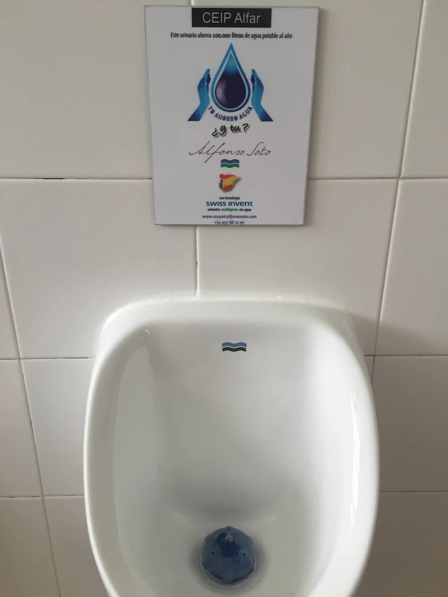 Urinario sin agua con cartel informativo en los aseos del CEIP Alfar de La Rambla (Córdoba)
